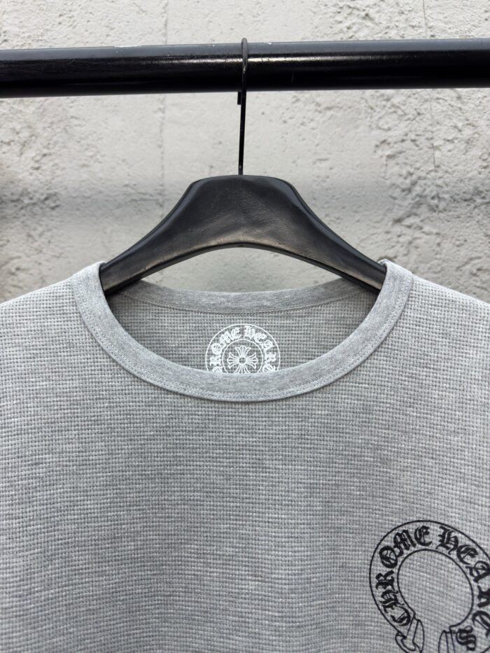 T-shirt grigia a costine con design grafico circolare, stile casual e moderno.