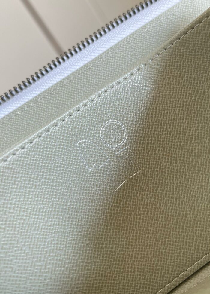 Portafoglio verde chiaro con zip e logo embossato, materiali di alta qualità e design elegante.