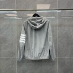 Giacca sportiva grigia con cappuccio e strisce bianche sulla manica, stile casual e moderno.
