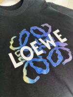 T-shirt Loewe nero con logo bianco e forme astratte colorate moderne.