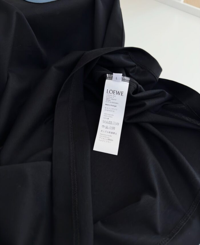 Dettaglio di abito nero di lusso Loewe, tessuto morbido ed elegante, con etichetta di alta moda.