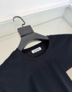 Maglietta nera LOEWE con colletto rotondo e design minimalista su appendiabiti elegante.