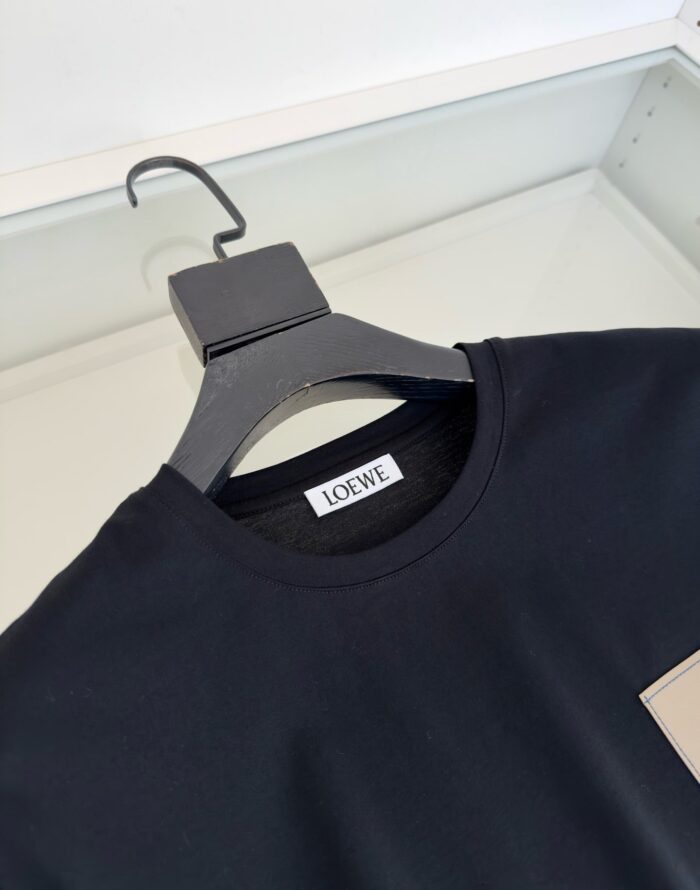 Maglietta nera LOEWE con colletto rotondo e design minimalista su appendiabiti elegante.
