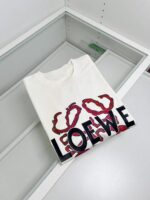 T-shirt bianco Loewe con grafica artistica e logo moderno, elegante display in vetro.