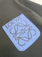 Logo LOEWE su patch blu sulla stoffa verde oliva, dettaglio di alta moda e lusso elegante.