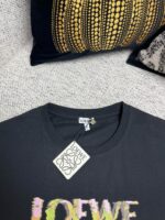 Maglietta LOEWE con logo multicolore, dettagli di lusso e sfondo elegante.