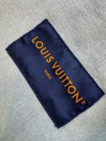 Etichetta Louis Vuitton in blu navy con scritte arancioni, simbolo di lusso e alta moda.