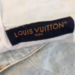 Etichetta Louis Vuitton su abito bianco di lusso, simbolo di eleganza e prestigio.