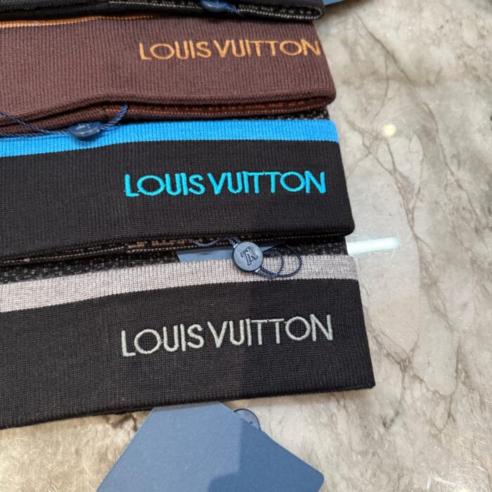 Bracciali elastici Louis Vuitton in vari colori su superfice di marmo di lusso.
