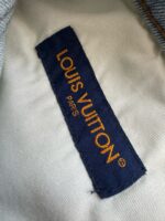 Etichetta Louis Vuitton in oro su sfondo navy, simbolo di lusso e qualità artigianale.