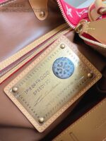 Borsa di lusso con dettaglio in pelle, hardware dorato e etichetta interna elegante.