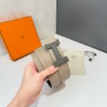 Cintura di lusso beige con fibbia moderna, confezione elegante e dettagli raffinati.