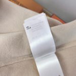 Etichetta di lusso su abbigliamento beige, dettagli eleganti e cura del livello premium.