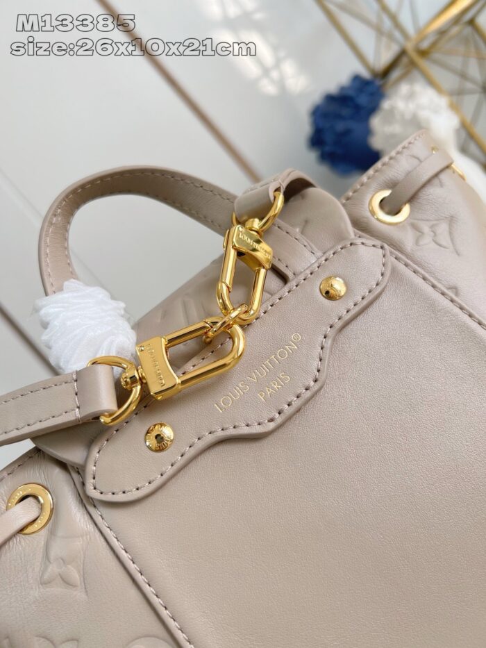 Borsa beige di lusso con dettagli in oro e pendente bianco, stile elegante e moderno.