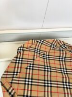 Tessuto tartan beige di lusso con dettagli eleganti in nero, rosso e bianco.