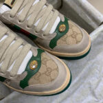 Sneaker di lusso beige con dettagli verdi, logo gold e design moderno e raffinato.