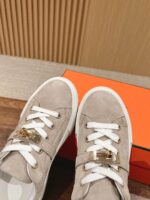 Sneaker di lusso in suede beige con fibbia dorata e suola bianca, stile elegante e versatile.