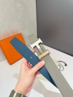 Cinture di lusso con fibbie moderne e minimaliste, in blu e grigio, in un ambiente esclusivo.