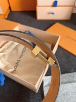 Cintura di lusso in pelle con fibbia oro, packaging Louis Vuitton elegante e raffinato.