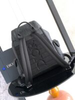 Zaino di lusso nero con dettagli texture e logo embossato su tavolo minimalista elegante.