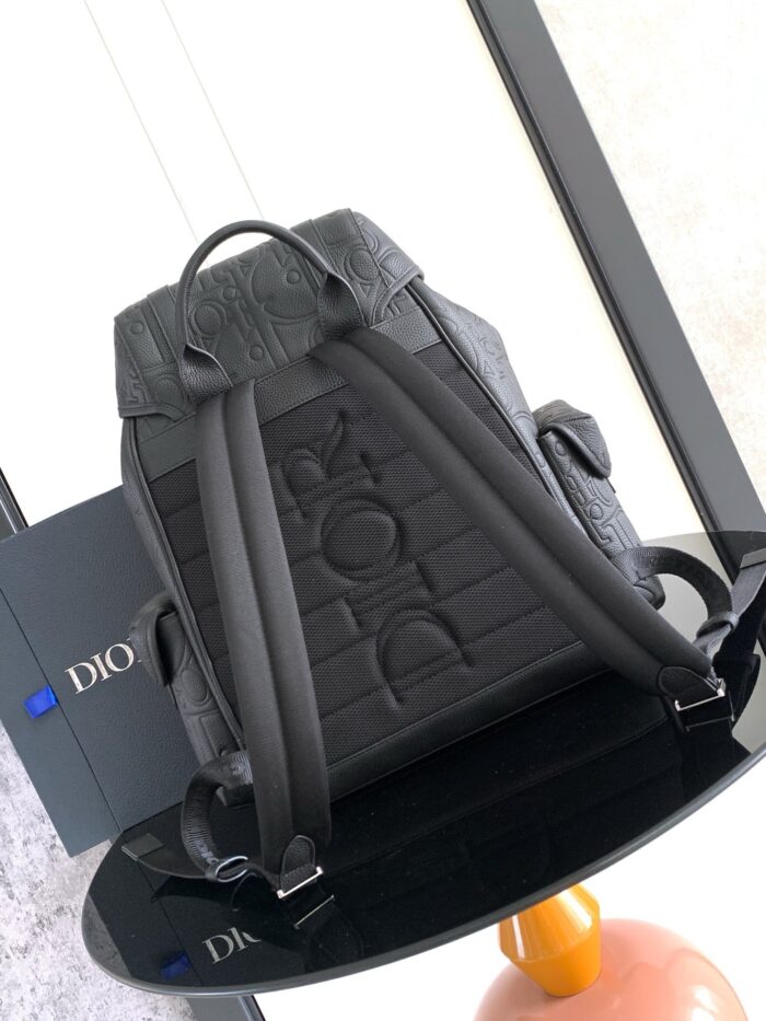 Zaino di lusso nero con dettagli texture e logo embossato su tavolo minimalista elegante.