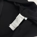 Giacchetto nero di lusso LOEWE con etichetta cura, tessuto morbido e dettagli eleganti.