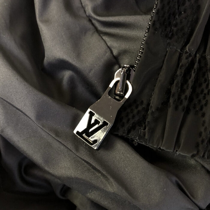 Zip di lusso con logo LV su tessuto nero satinato, dettaglio elegante e raffinato.