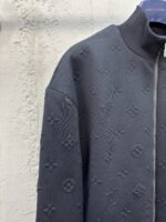 Giacca nera di lusso con motivi embossati, zip frontale e stile moderno ed elegante.