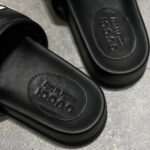 Sandali Gucci in pelle nera, design moderno, logo inciso, stile elegante e comfort.