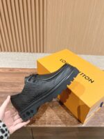 Scarpa nera di design con suola chunky e confezione di lusso arancione.