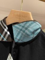 Maglietta polo nera Burberry con colletto check colorato, dettagli di lusso e stile raffinato.