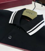 Polo nero di lusso Gucci con colletto a righe bianche e dettagli eleganti.