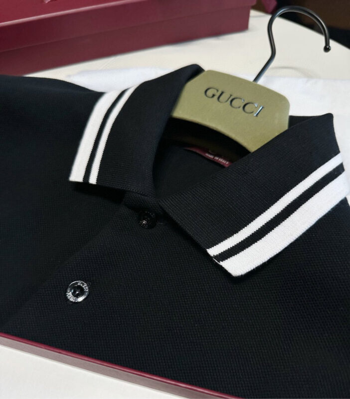 Polo nero di lusso Gucci con colletto a righe bianche e dettagli eleganti.