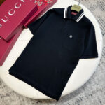 Polo nero di lusso con dettagli Gucci e elegante packaging rosso.