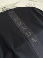 Maglietta nera Prada con logo lucido sulla schiena, stile moderno e di lusso.