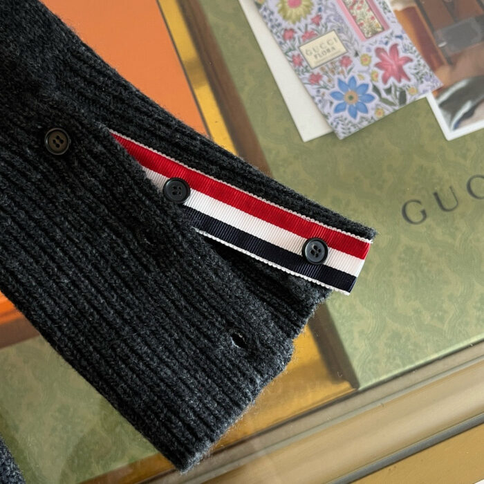 Maglione nero a coste con dettagli a strisce rosso, bianco e blu, stile casual ed elegante.
