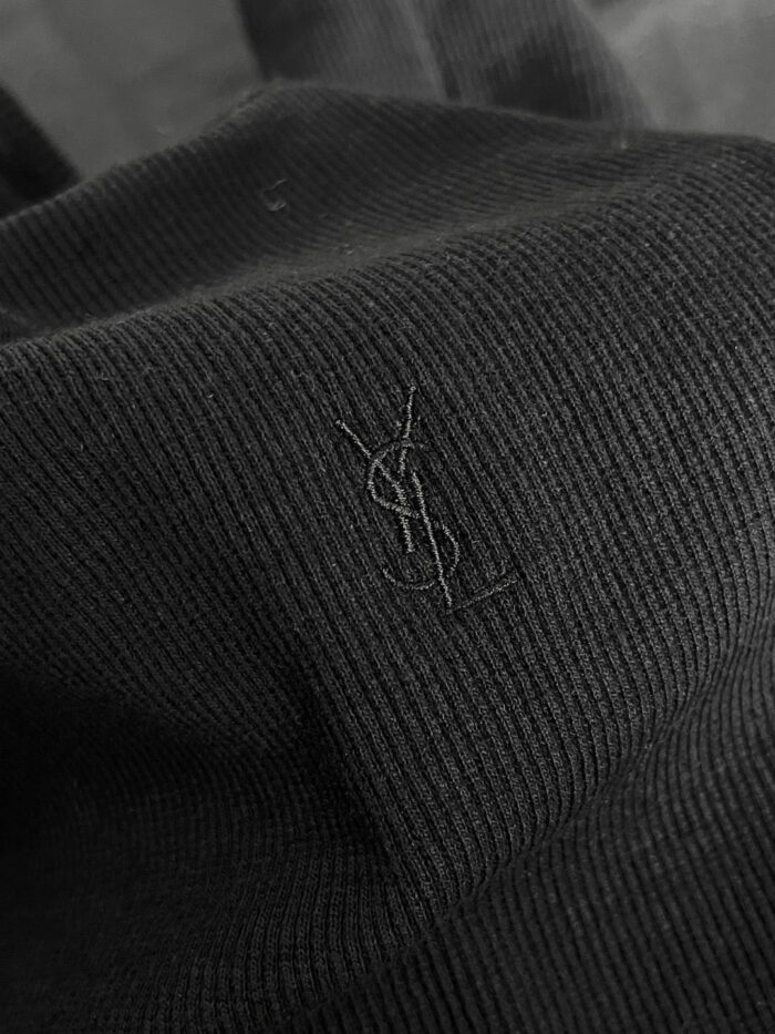 Logo Yves Saint Laurent su tessuto nero lussuoso con dettaglio ricamato sottile.