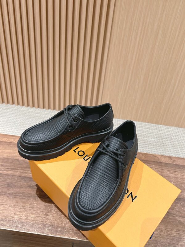 Scarpe nere di lusso moderne su scatola arancione, elegante sfondo in legno, dettagli raffinati.