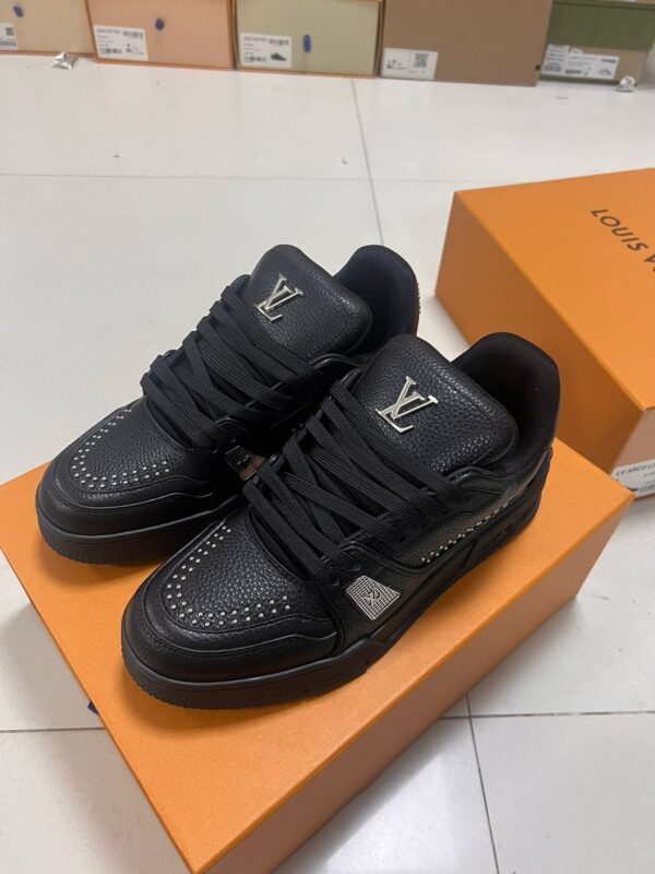 Sneakers nere di lusso Louis Vuitton con logo, su scatola arancione elegante e moderno.