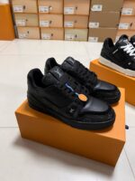 Sneakers nere di lusso con dettagli colorati, su scatole arancioni in ambiente elegante e moderno.