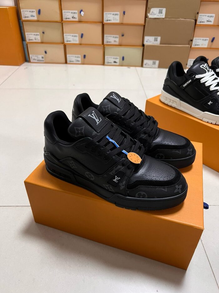 Sneakers nere di lusso con dettagli colorati, su scatole arancioni in ambiente elegante e moderno.