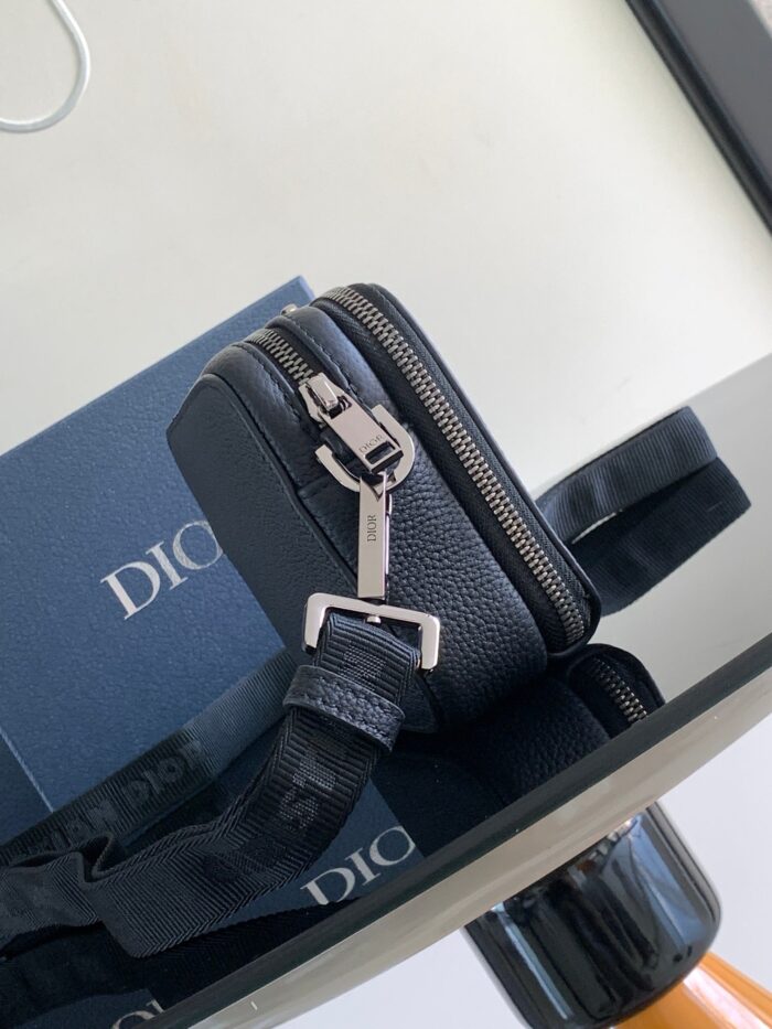 Borsa nera di lusso con scatola Dior e dettagli eleganti su superficie riflettente