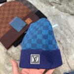 Berretto di lusso blu con design checkered, dettaglio logo e stile moda elegante.