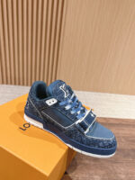 Sneaker blu di lusso con dettagli in pelle e suola trasparente su scatola arancione.