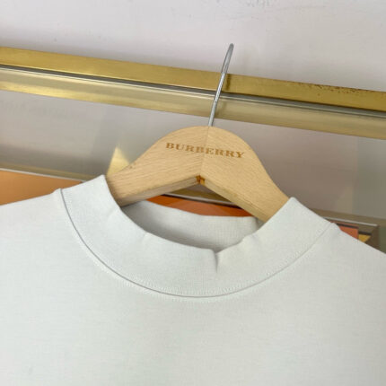 Maglia leggera Burberry su appendiabiti di lusso in ambiente elegante.