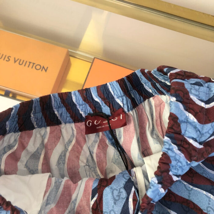 Dettaglio di abbigliamento Gucci con motivo colorato e branding di lusso,vsul sfondo Louis Vuitton.