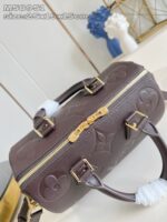 Borsa cilindrica in pelle marrone con dettagli dorati e accessori bianchi eleganti.