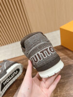 Sneaker di lusso in pelle marrone con dettagli di cuciture e branding bianco in evidenza.