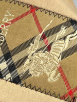 Tessuto Burberry con ricamo di guerriero e pattern checkered nero, rosso e beige, elegante e di lusso.