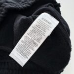 Etichetta Burberry su maglione nero morbido, dettagli di cura e eleganza di lusso.